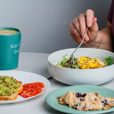 A hand holding a fork, meals and a drink.