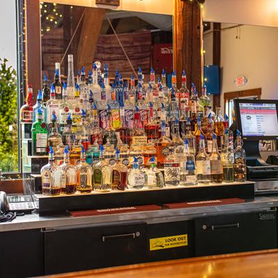 Back bar with multiple tiers of liquor bottles and integrated computer POS system.