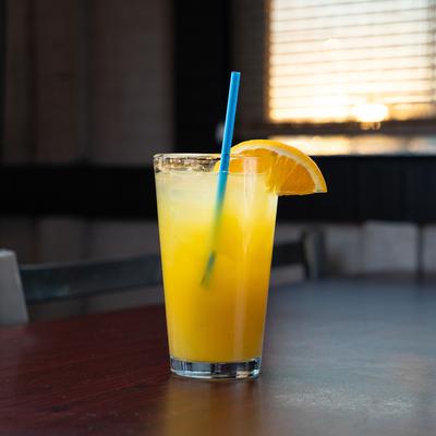 A glass of Orange Crush cocktail, garnished with an orange wedge and blue straw.