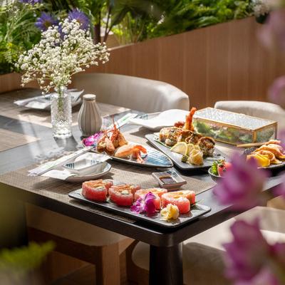 Atable with served food, surrounded by restaurant's floral and greenery decor.