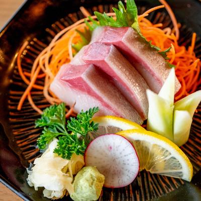 Yellowtail Sashimi with various garnishes and condiments.