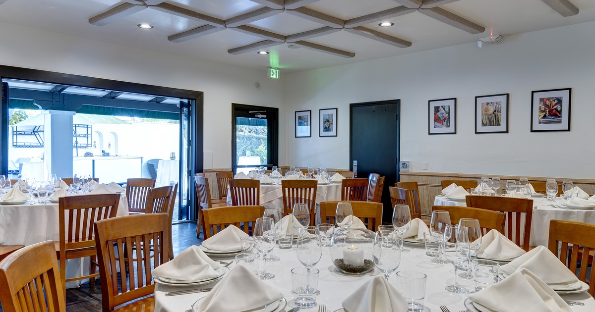 dining room with round tables set with glassware, plates, cutlery and folded napkins