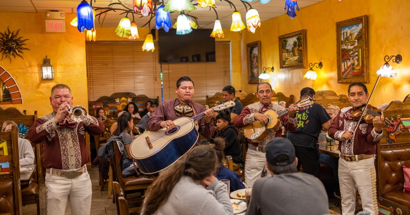 Interior, a live band playing for customers sitting at tables, lights, paintings
