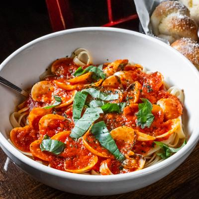 Pasta with tomato sauce, clams and fresh basil leaves.