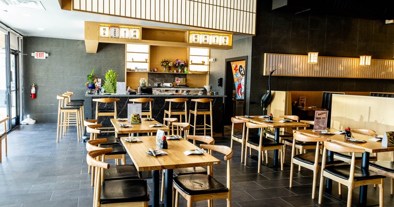 A modern Japanese restaurant - a sushi counter, wood tables & chairs, shoji-style decor