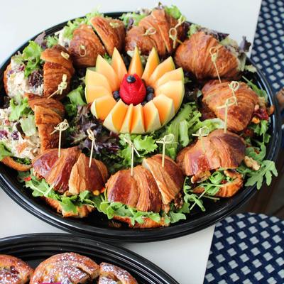 Croissant sandwich platter garnished with melon wedges and berries