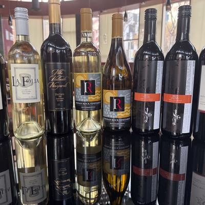 Assorted wine bottles displayed on a reflective surface.