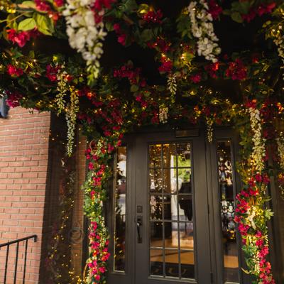 Elegant restaurant entrance decorated with flowers and string lights.