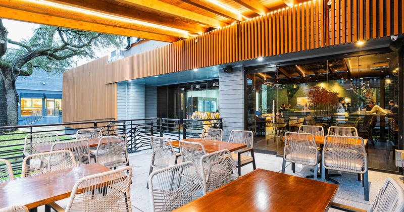 Outdoor dining area with wooden tables and wicker chairs.