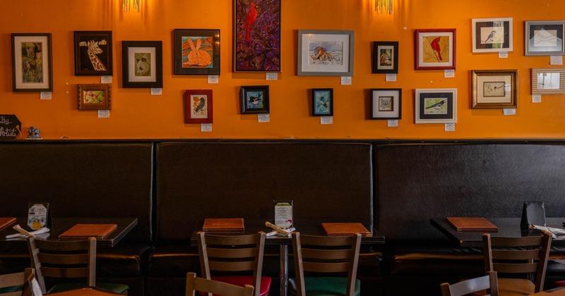 Interior, banquette seating area, tables and chairs, framed pictures on the wall
