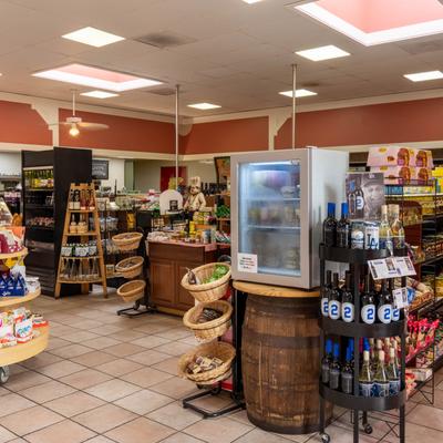 Grocery store interior with wine displays, refrigerated case, and stocked shelves.