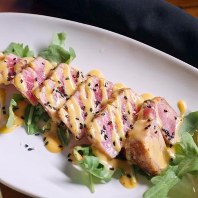 Ahi Tuna Appetizer topped with sesame seeds and bang bang sauce.