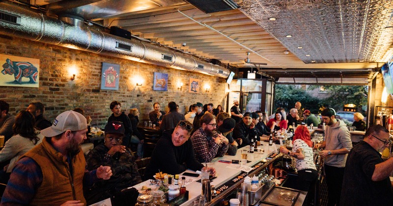 Interior, bar counter and tables, crowd of people enjoying drinks and talking