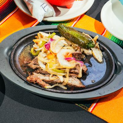 Sizzling steak fajitas topped with onions, bell peppers, and a charred jalapeno.