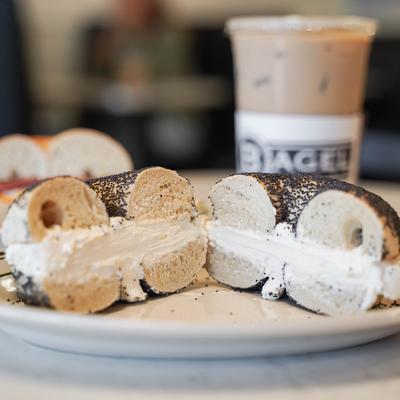 A plate with a cut bagel with cream.