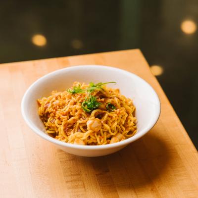 Noodles served in a bowl with herbs.