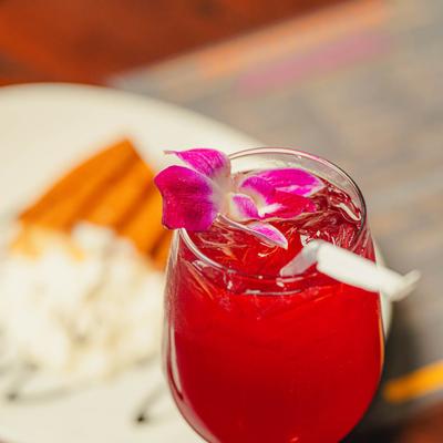 Close-up of a red cocktail with orchid garnish.