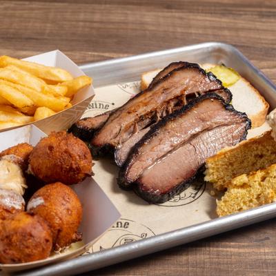 Three brisket slices served with French fries, toast, cornbread, and hush puppies.