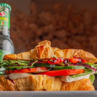 Caprese croissant sandwich with fresh mozzarella, tomatoes, basil, and balsamic glaze.