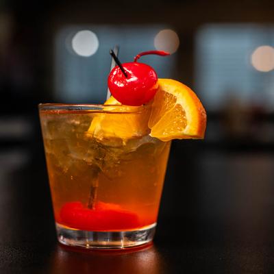 Old Fashioned garnished with cherry and orange slice perched on the rim.