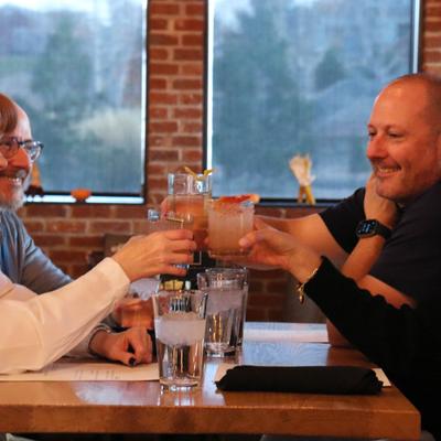 People clinking drinks at the restaurant table.