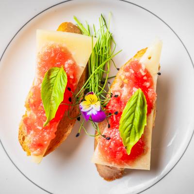 A bruschetta with cheese, tomato topping, and fresh basil.
