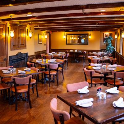 Well-lit dining room with set tables and upholstered chairs, showcasing a warm, inviting atmosphere.