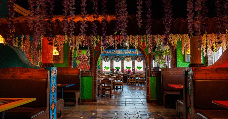 Interior with hanging flowers, murals, and arched passages leading to seating areas
