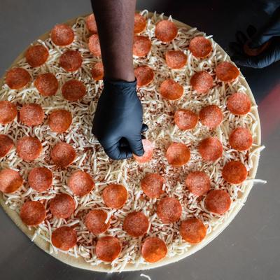 The pepperoni pizza being prepared for baking.