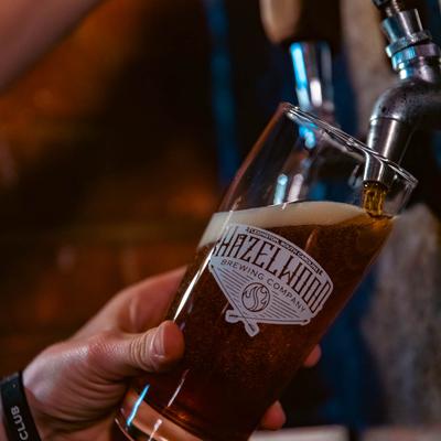A hand pouring a glass of beer from the dispensary.