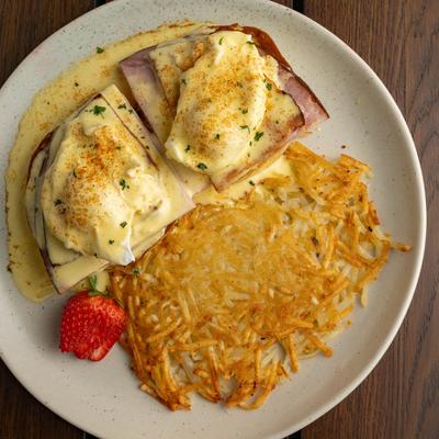 Eggs Benedict with hollandaise sauce and crispy hash browns.