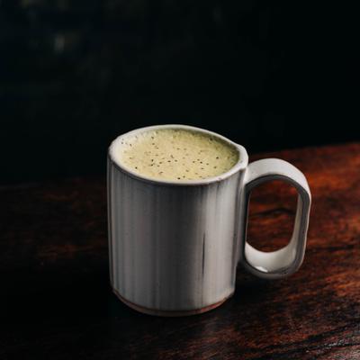 A creamy matcha latte served in a gray ribbed ceramic mug.