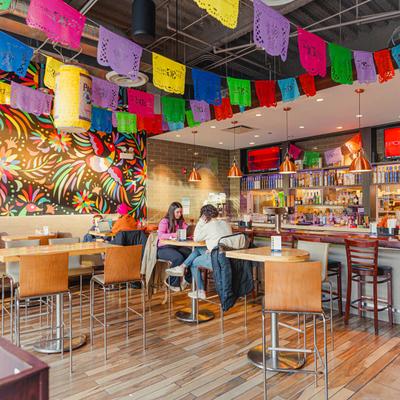 Vibrant restaurant interior with bar seating, colorful banners, and wall mural.