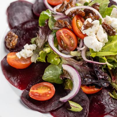 Beet salad with greens, cherry tomatoes, and goat cheese.