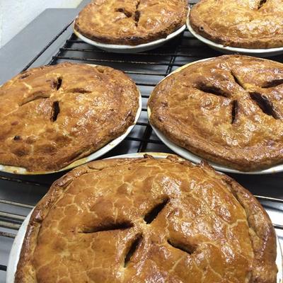 Fresh baked pies cooling on metal racks.