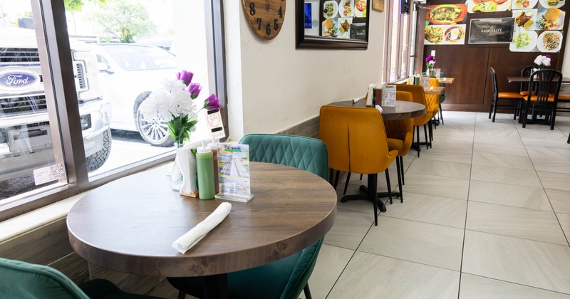 Interior, seating area by the windows, round tables for two