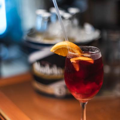 Red sangria served with orange slice in a wine glass.