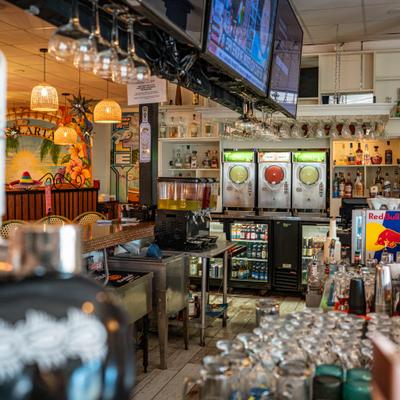 Colorful bar interior with slush machines and bottles on display.