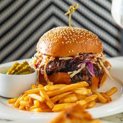 BBQ Short Rib Sandwich served with fries and pickle slices.