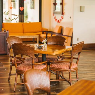 Seating area with wicker chairs and orange sofa in the background.
