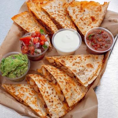 Platter of quesadillas served with guacamole, beans, sour creme and pico de gallo.