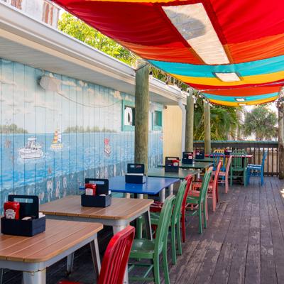 Exterior, wooden terrace over the water, tables, chairs, sun protection fabric.