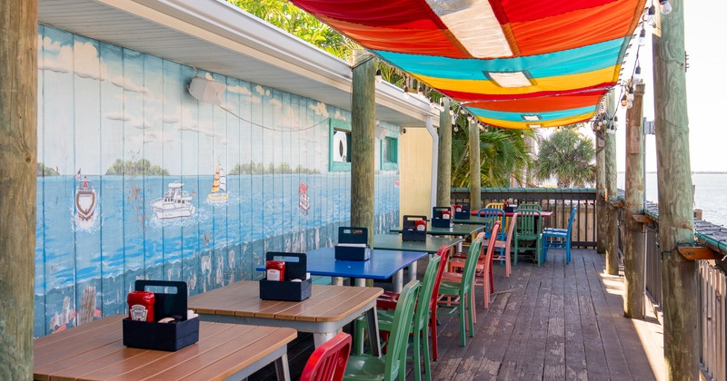 Exterior, wooden terrace over the water, tables, chairs, sun protection fabric