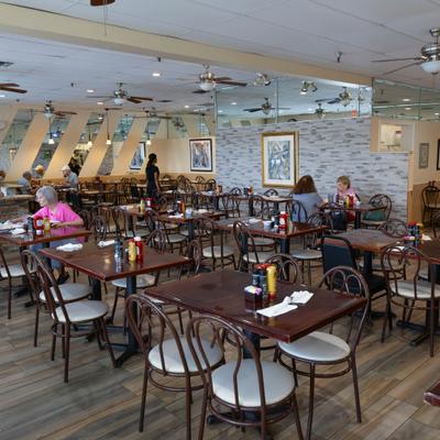 Interior with wooden tables, metal chairs, and a patterned wall finish.