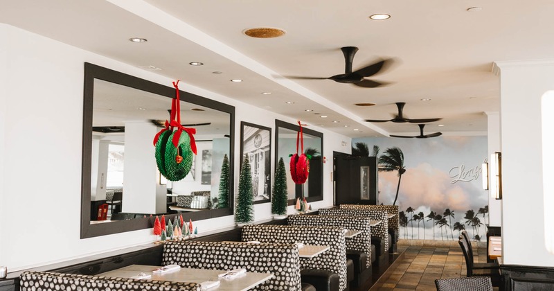 Interior of a restaurant with booths, festive decorations, and a palm tree mural