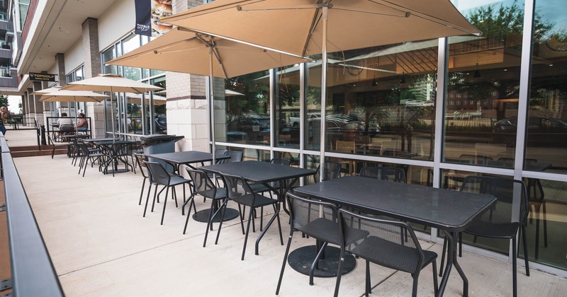 Exterior, patio, tables and chairs under parasols, front of the restaurant, glass windows