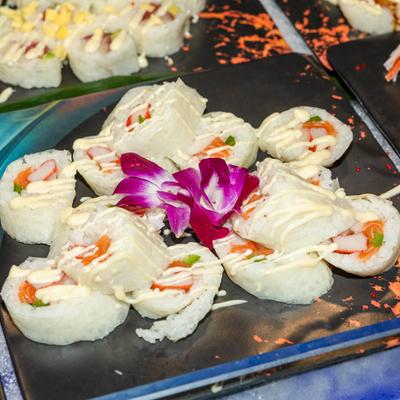 Sushi roll wrapped in thin slices of fresh cucumber, garnished with purple orchid.