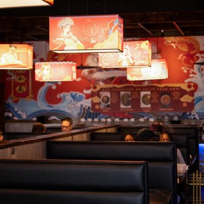 A dining room scene featuring mural art on a wall, hanging lanterns, and dining booths.