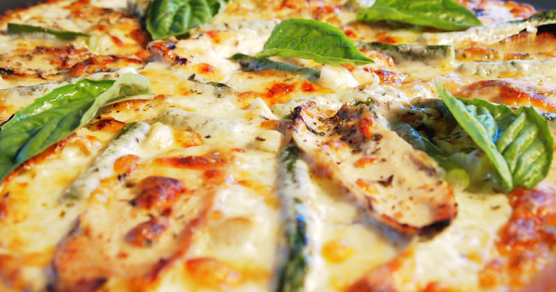 White pizza with fresh basil leaves on top.