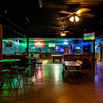 A lively local bar featuring pool tables, neon lights, and TVs.